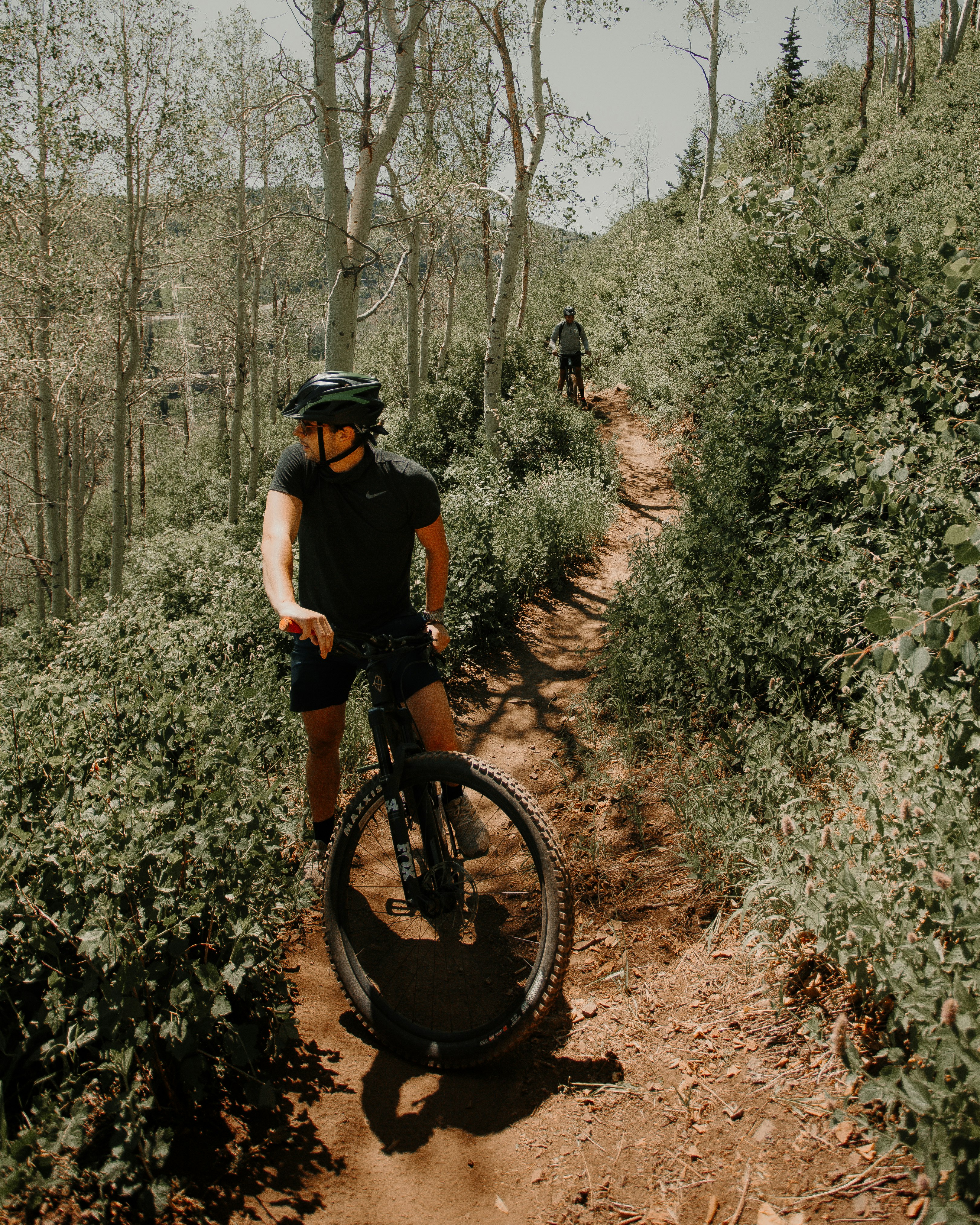 man in black t-shirt riding bicycle on forest during daytime